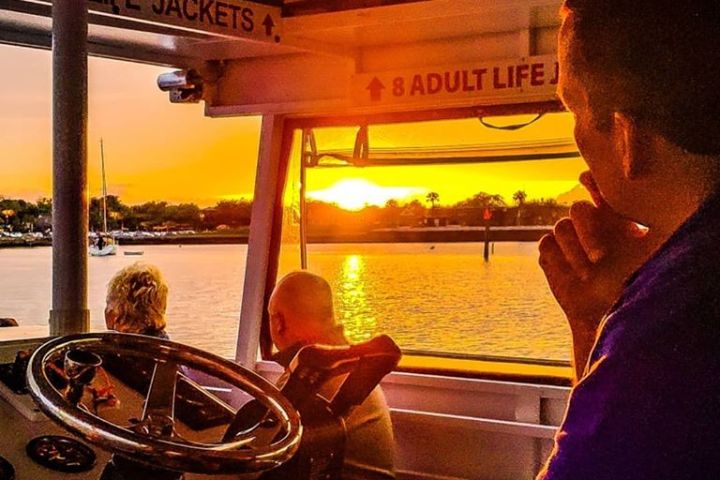 orange sunset from boat with steering wheel
