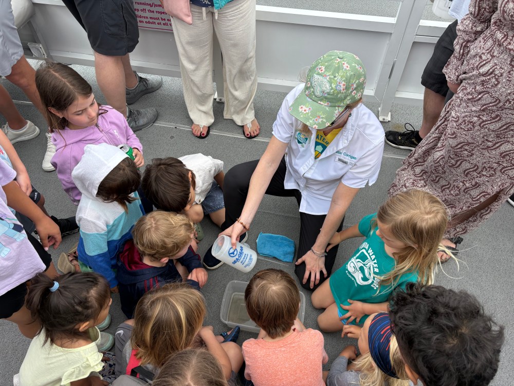 Instructor showing kids sea items on a deck.