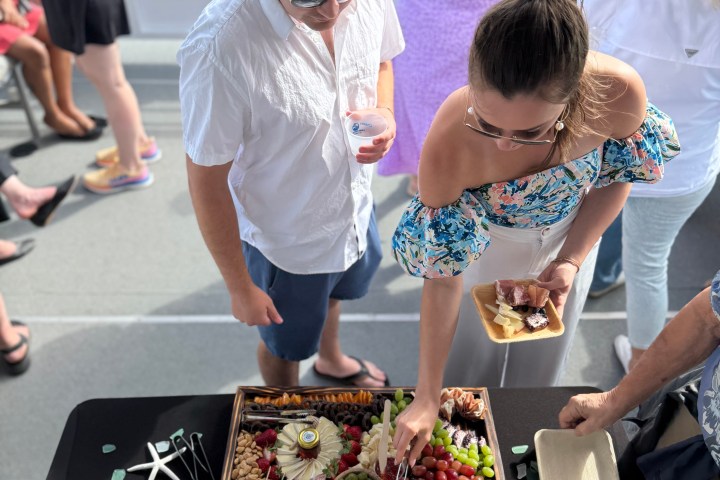 People enjoy a charcuterie board on a boat with sea in the background.