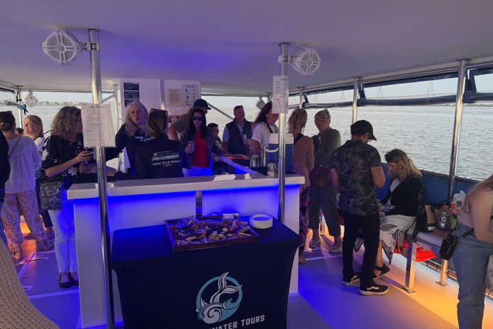 People enjoying a tour on a boat with a snack table and scenic water view.