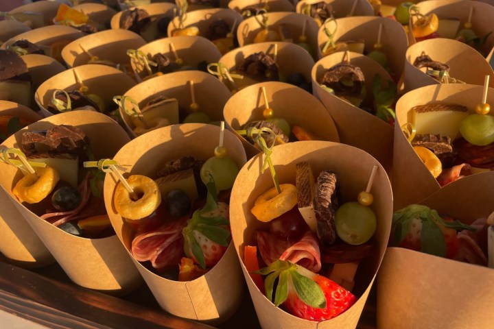 Cones filled with fruit, cheese, and snacks arranged in rows.