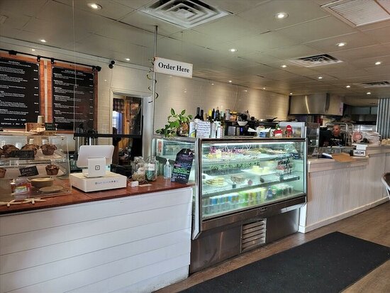 Café counter with pastries, menu board, and refrigerated display case.