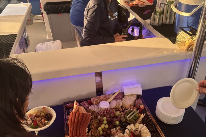 People enjoying snacks and drinks at a boat bar with a large charcuterie board.