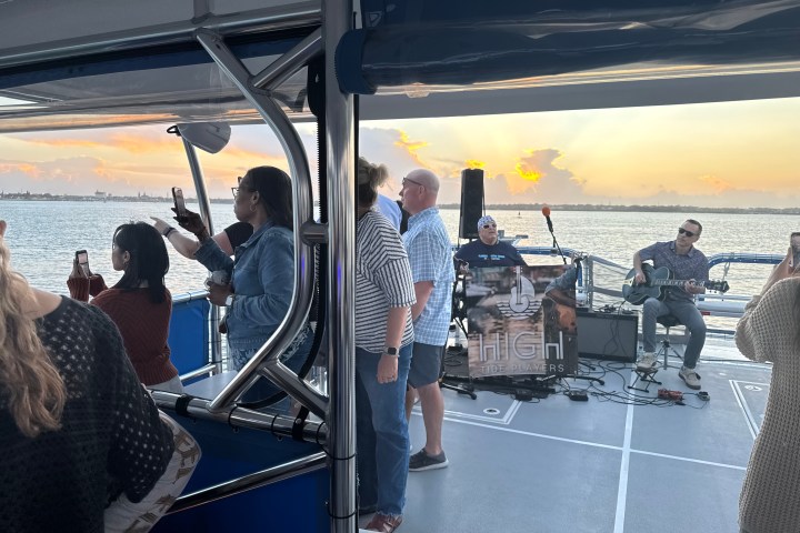 People on a boat enjoying a sunset with live music performance.