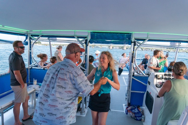 People enjoying a boat cruise with a woman and man dancing in the foreground.