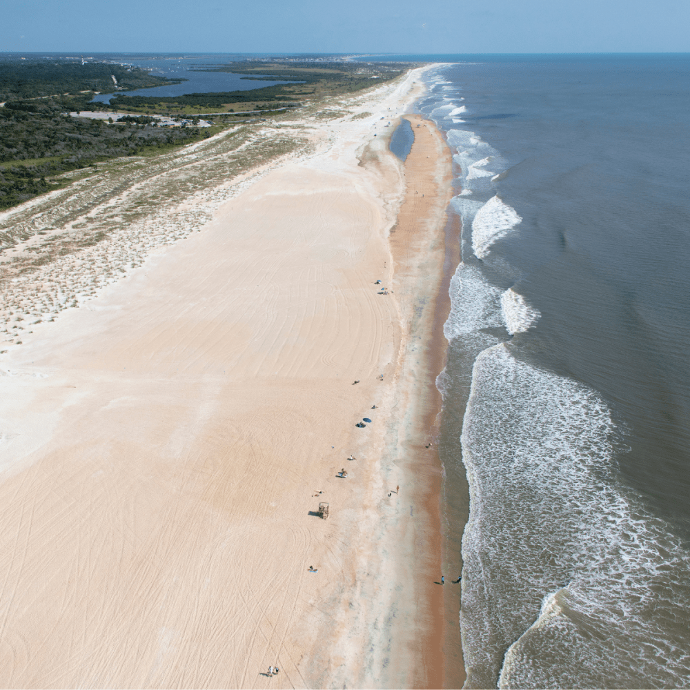 Aerial view of a long, sandy beach with waves.