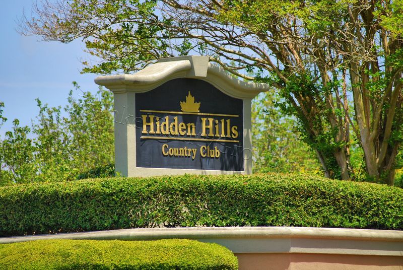 Hidden Hills Country Club sign surrounded by lush greenery.