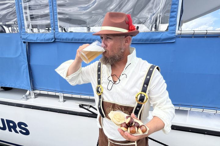 Person in traditional outfit eating food on a boat deck.