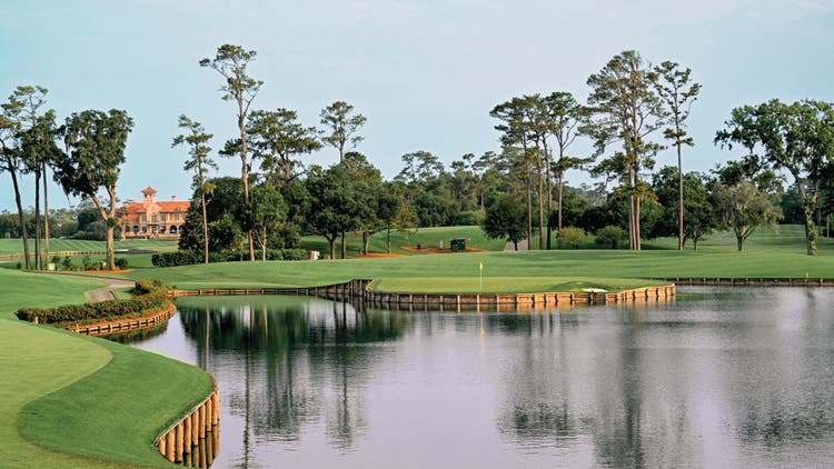 Golf course with water hazard and distant clubhouse.