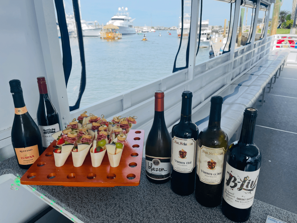 Wine bottles, appetizers, and a marina view on a boat.