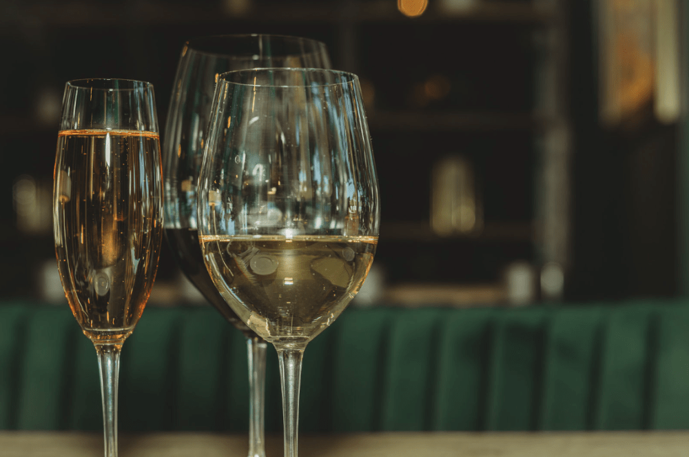 Close-up of three wine glasses with sparkling and white wine on a table.